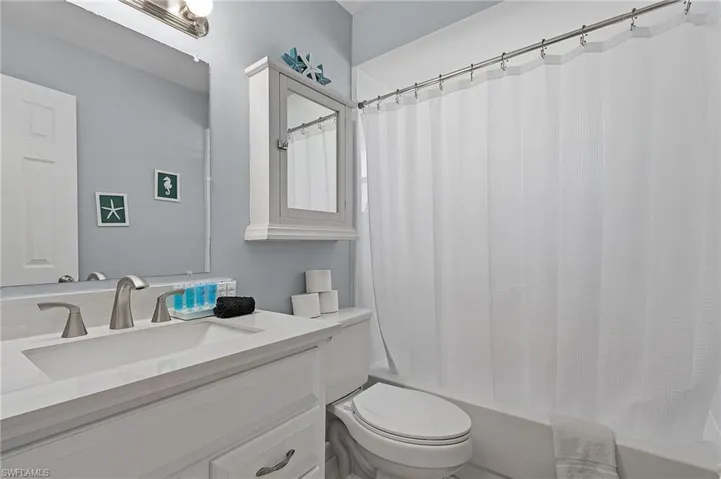 Full bathroom with vanity, shower / bath combination with curtain, and toilet