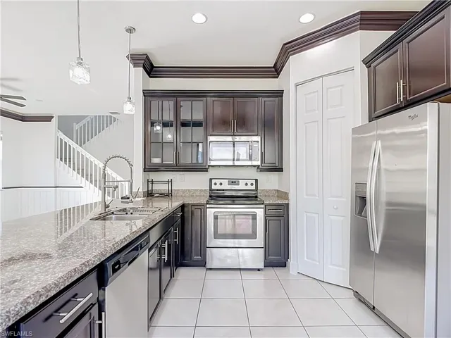 Kitchen featuring dark wood cabinetry, light-colored granite countertops, and stainless steel appliances