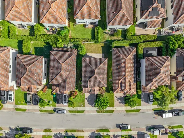 Residential street featuring multiple properties with terracotta tile roofs, paved driveways, and manicured landscaping
