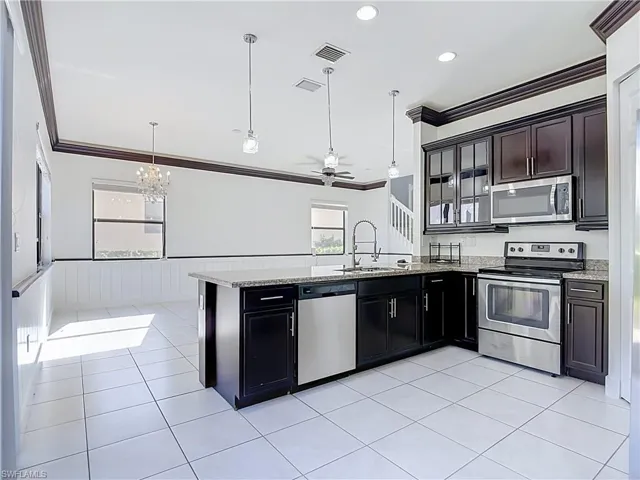 Kitchen featuring dark wood cabinetry, stainless steel appliances, and a granite-topped island