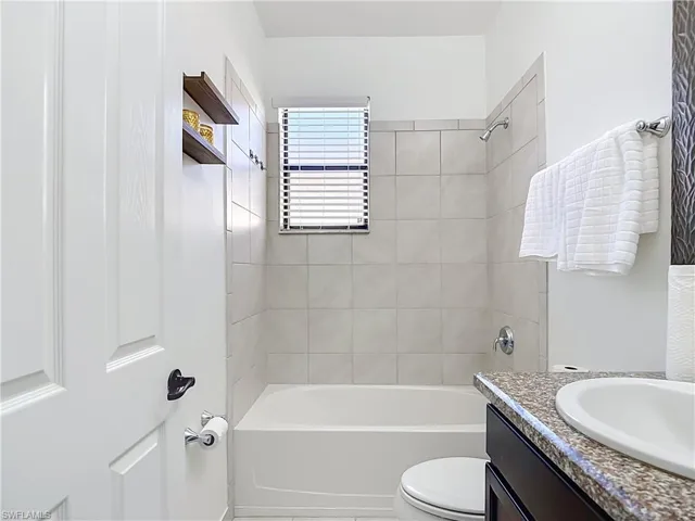 Bathroom featuring a white tub, tiled shower surround, and a window with blinds