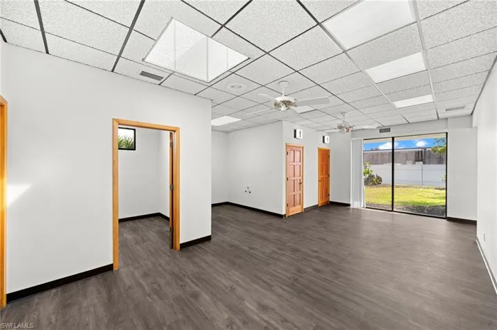 Unfurnished room with a paneled ceiling, ceiling fan, and dark wood-type flooring