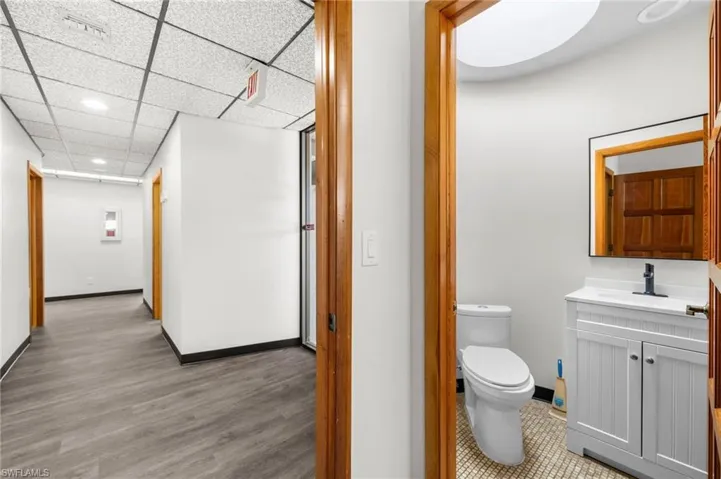 Bathroom featuring hardwood / wood-style floors, vanity, a drop ceiling, and toilet
