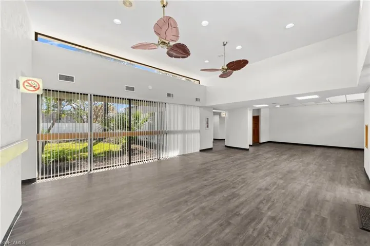 Empty room with ceiling fan, a towering ceiling, and dark wood-type flooring