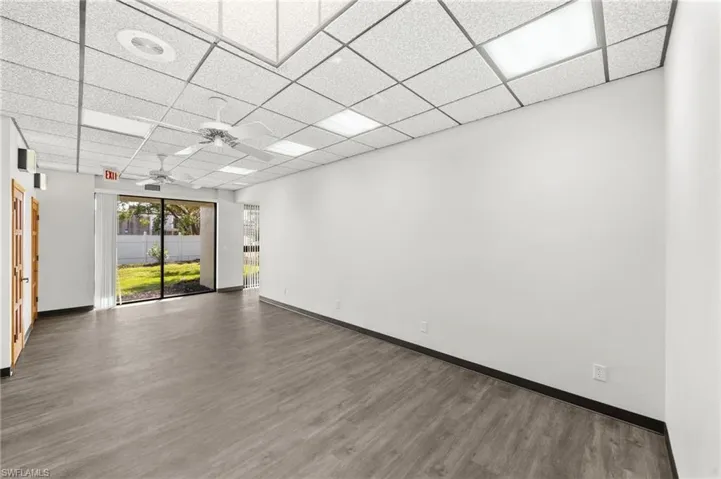 Empty room featuring ceiling fan, a drop ceiling, and dark hardwood / wood-style floors