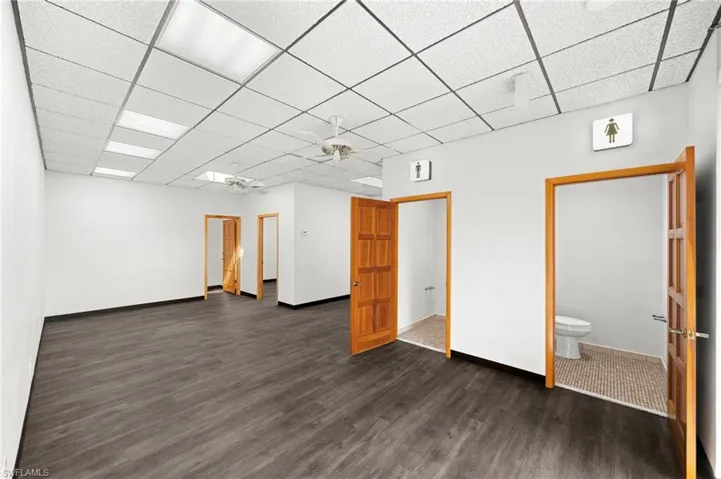 Unfurnished room featuring a paneled ceiling, ceiling fan, and dark wood-type flooring