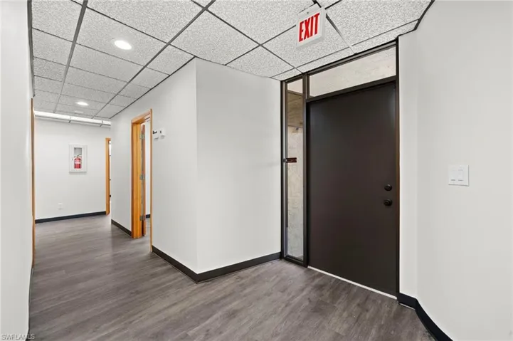 Corridor featuring a paneled ceiling and dark wood-type flooring
