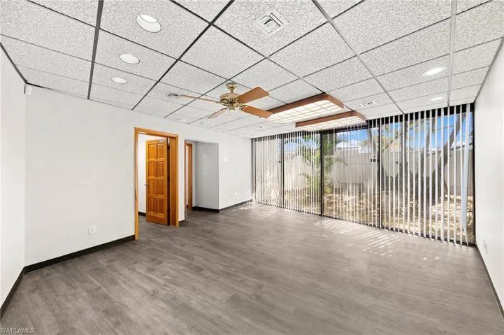 Unfurnished room featuring a paneled ceiling, dark hardwood / wood-style floors, and ceiling fan