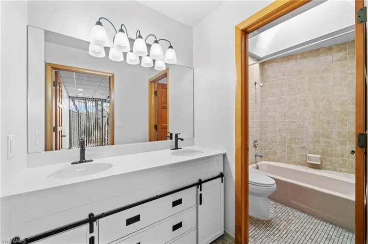 Full bathroom with tile patterned floors, tiled shower / bath, vanity, and toilet