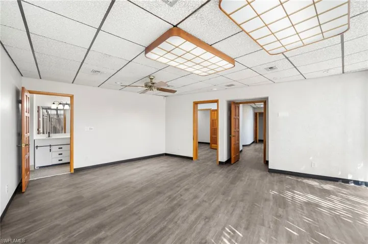 Empty room with dark hardwood / wood-style flooring, ceiling fan, and a paneled ceiling