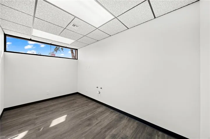 Spare room with a drop ceiling and dark hardwood / wood-style floors