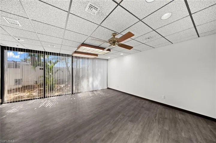 Empty room featuring a paneled ceiling, ceiling fan, and dark wood-type flooring