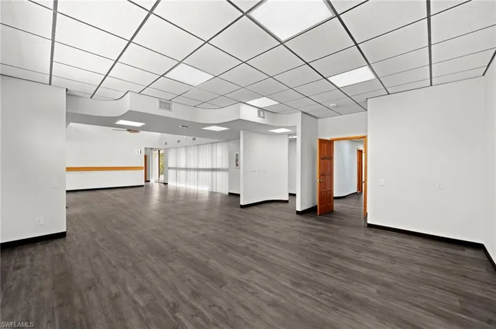 Unfurnished room with dark hardwood / wood-style flooring and a paneled ceiling