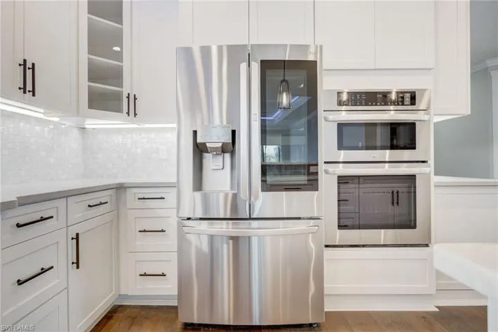 Kitchen featuring white cabinetry, decorative light fixtures, light hardwood / wood-style floors, and appliances with stainless steel finishes