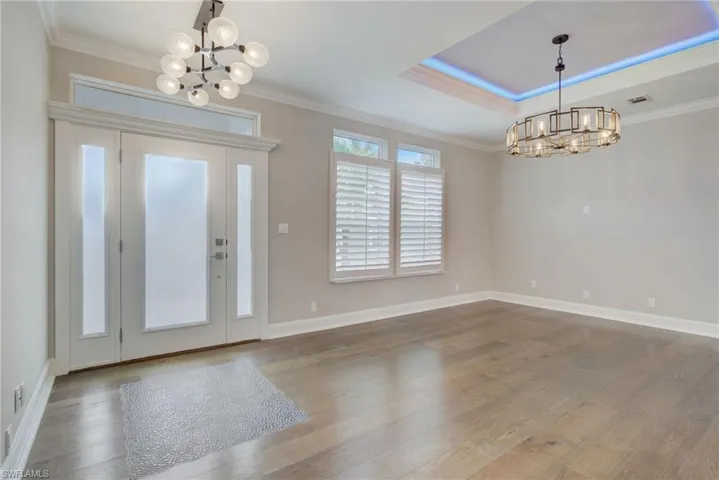 Foyer entrance featuring an inviting chandelier, a tray ceiling, and crown molding