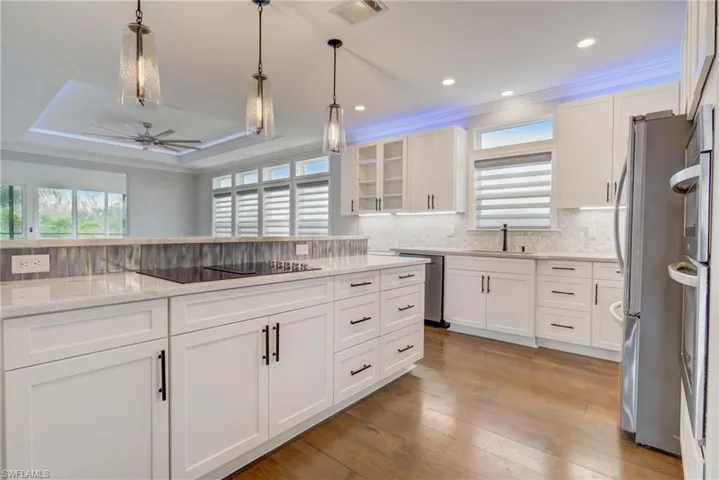 Kitchen with dishwasher, white cabinets, and a tray ceiling