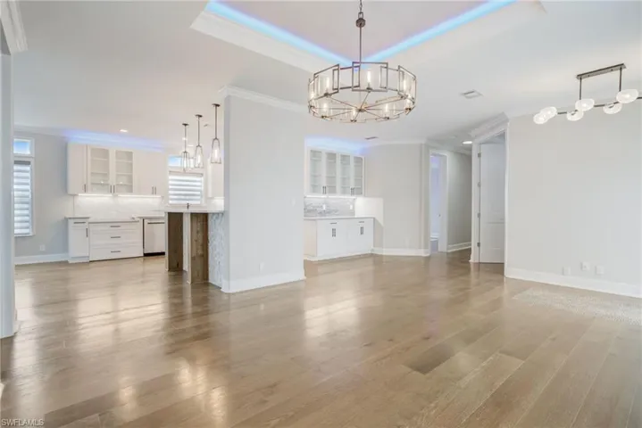 Unfurnished living room with ornamental molding, a chandelier, hardwood / wood-style floors, and plenty of natural light