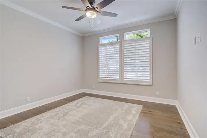 Unfurnished room featuring crown molding, ceiling fan, and dark hardwood / wood-style flooring