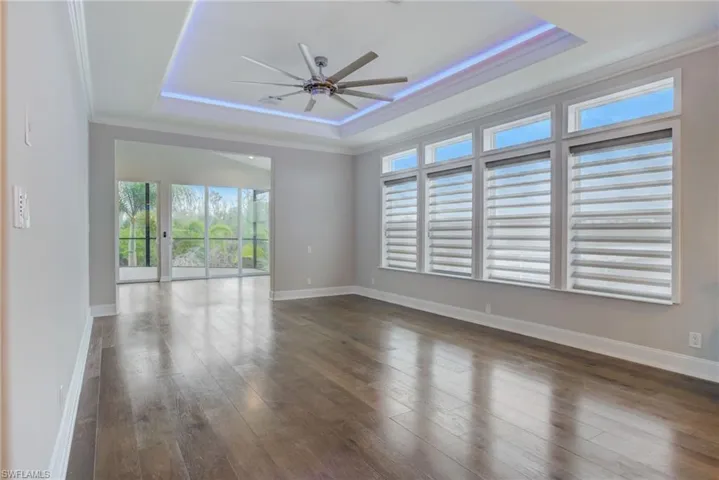 Spare room featuring crown molding, ceiling fan, dark hardwood / wood-style flooring, and a raised ceiling