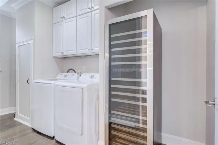 Laundry room featuring cabinets, beverage cooler, washer and dryer, and light wood-type flooring