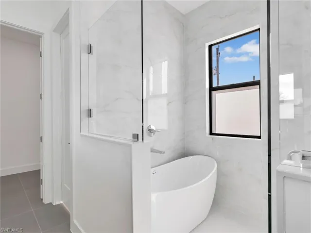 Full bathroom featuring a soaking tub, tile walls, and tile patterned floors