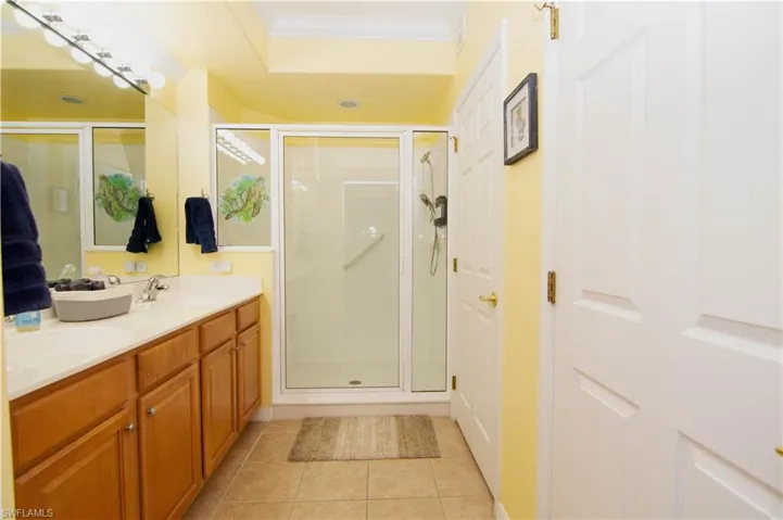 The spacious en suite Primary Bathroom features a double vanity with terrific cabinet storage, a large shower with glass door, a integrated walk-in closet with luxury vinyl plank flooring, a separate water closet, ceramic tile flooring, and crown molding.