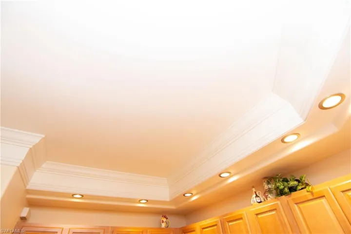 Detailed view of crown molding, recessed lighting, and a raised ceiling.