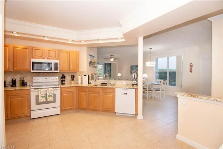 Kitchen features bright recessed lighting, crown molding, a large pantry, a washer and dryer closet, gleaming granite and coordinating backsplash, breakfast bar, a new dishwasher and microwave oven, and is fully stocked and outfitted turnkey!