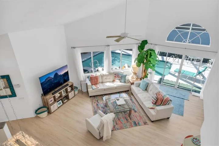 Living room featuring a ceiling fan, wood finished floors, and vaulted ceiling