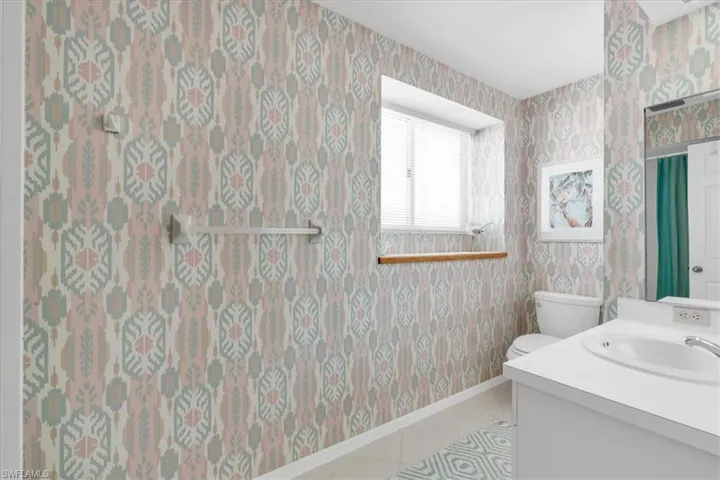 Bathroom with vanity, wallpapered walls, and light tile patterned floors