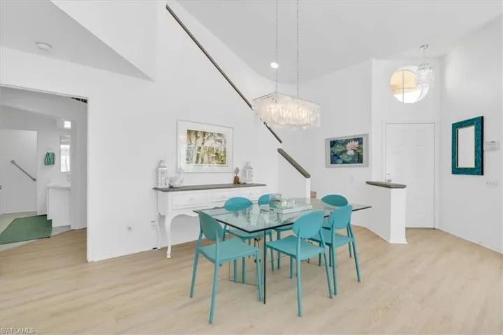 Dining space with light wood-type flooring, a chandelier, and vaulted ceiling