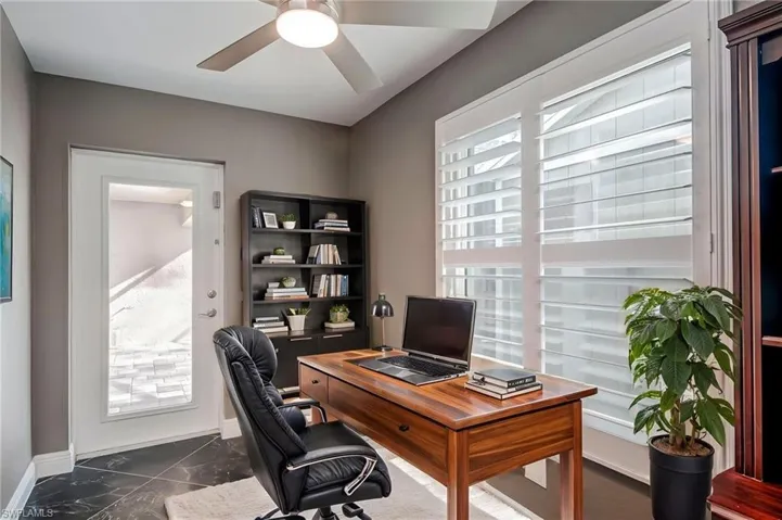 Office featuring dark marble finish floors, plenty of natural light, and a ceiling fan