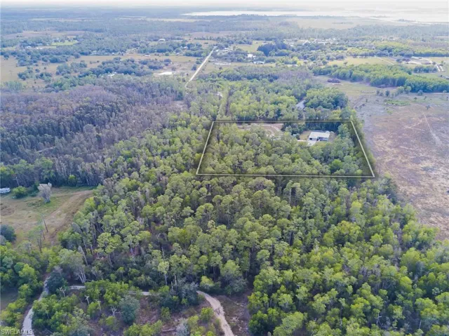 Aerial view of property's location with property parcel outlined and a heavily wooded area