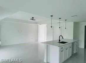 Kitchen island with white shaker cabinetry, an undermount sink, and matte black hardware