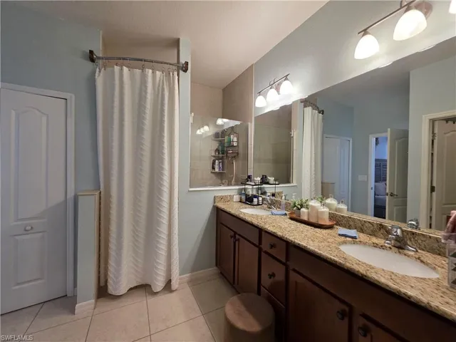 Bathroom featuring double vanity, curtained walk in shower