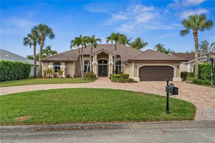 Ranch-style home featuring stucco siding, a garage, curved driveway, and a tiled roof