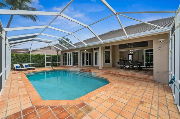 View of swimming pool featuring a lanai, patio surround, a sunroom, and outdoor dining area