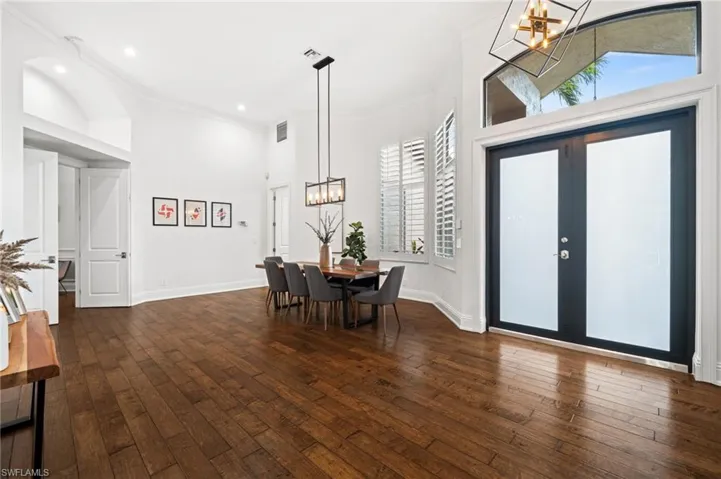 Dining room with ornamental molding, a chandelier, a high ceiling, dark wood-style floors, and french doors