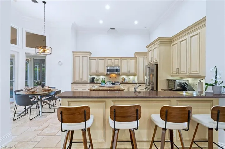 Kitchen with a kitchen bar, cream cabinets, a peninsula, tasteful backsplash, and crown molding