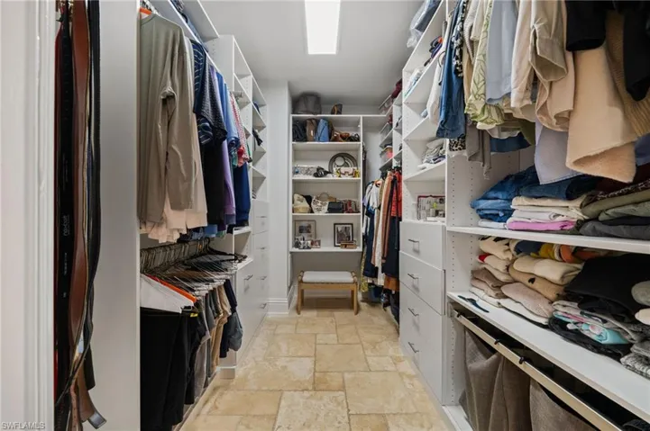 Walk in closet with light stone finish flooring