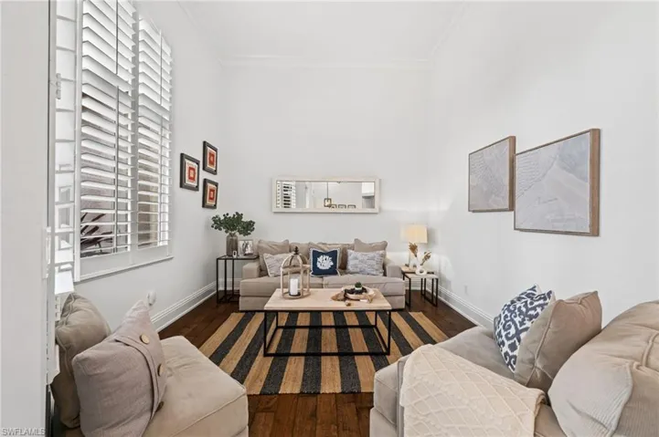Living area featuring dark wood-type flooring and crown molding
