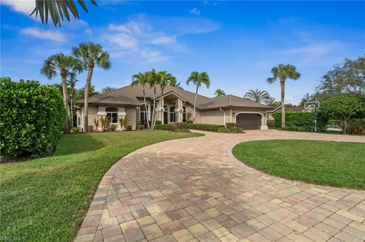 Ranch-style house with a front lawn, curved driveway, stucco siding, and an attached garage