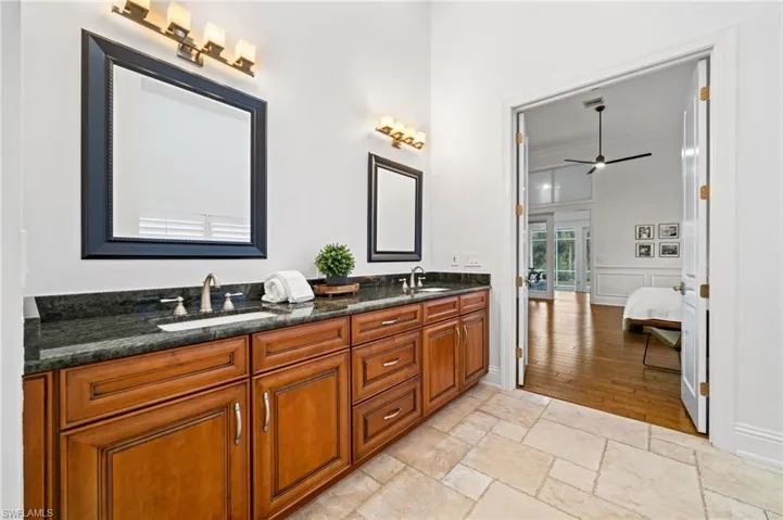 Bathroom with double vanity, stone tile floors, and ceiling fan