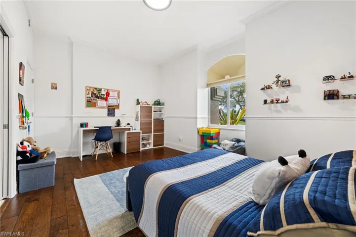 Bedroom featuring crown molding, dark wood-style floors, and an office area