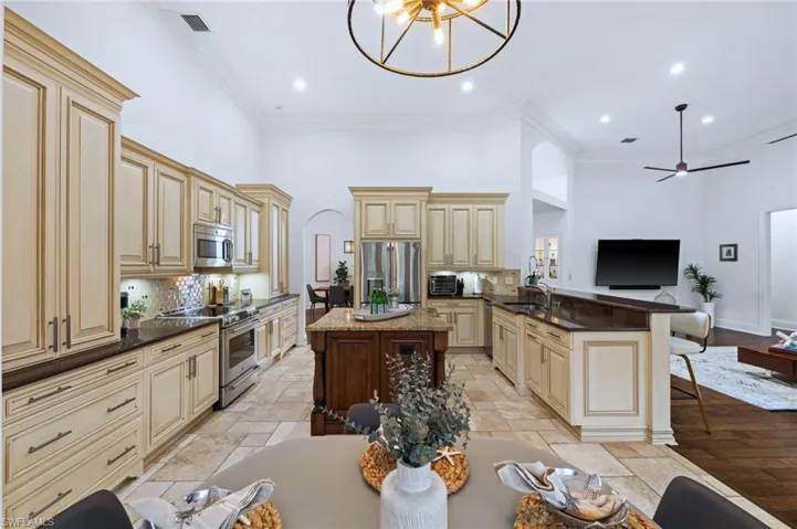 Dual tone kitchen featuring a kitchen breakfast bar, open floor plan, backsplash, a high ceiling, and a peninsula