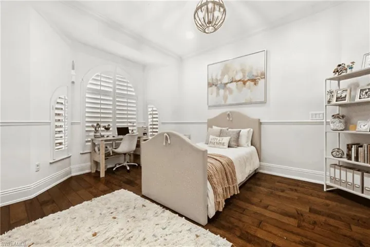 Bedroom with dark wood finished floors, a chandelier, and a desk