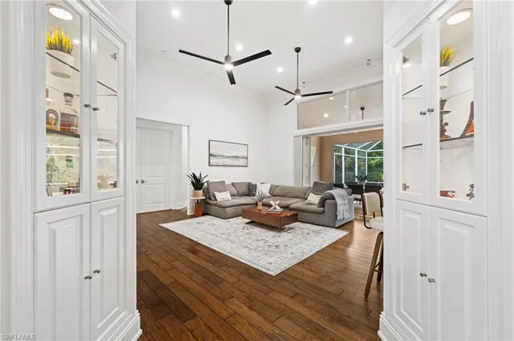 Living area featuring dark wood-style floors, recessed lighting, crown molding, a ceiling fan, and a high ceiling