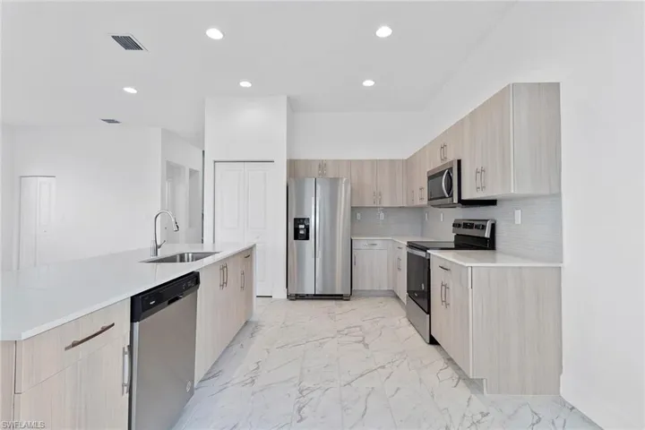 Kitchen with modern cabinets, stainless steel appliances, tasteful backsplash, and quartz countertops