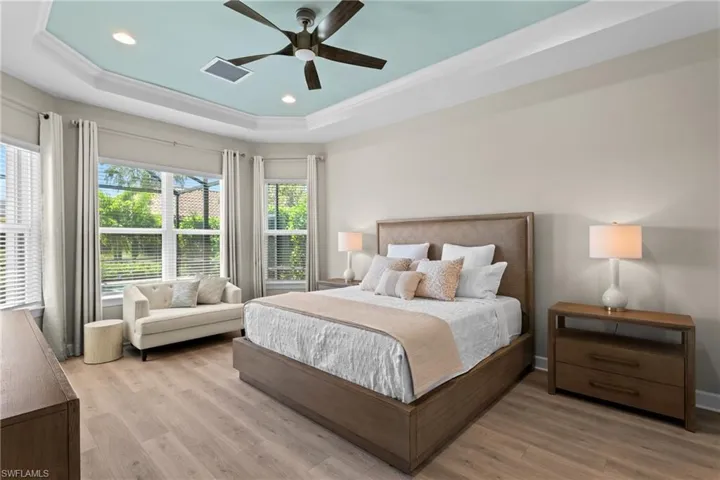 Bedroom featuring a raised ceiling, recessed lighting, light wood-style floors, and visible vents