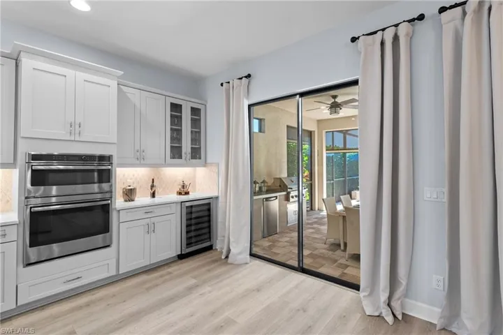Kitchen with light countertops, wine cooler, tasteful backsplash, appliances with stainless steel finishes, and light wood-style floors